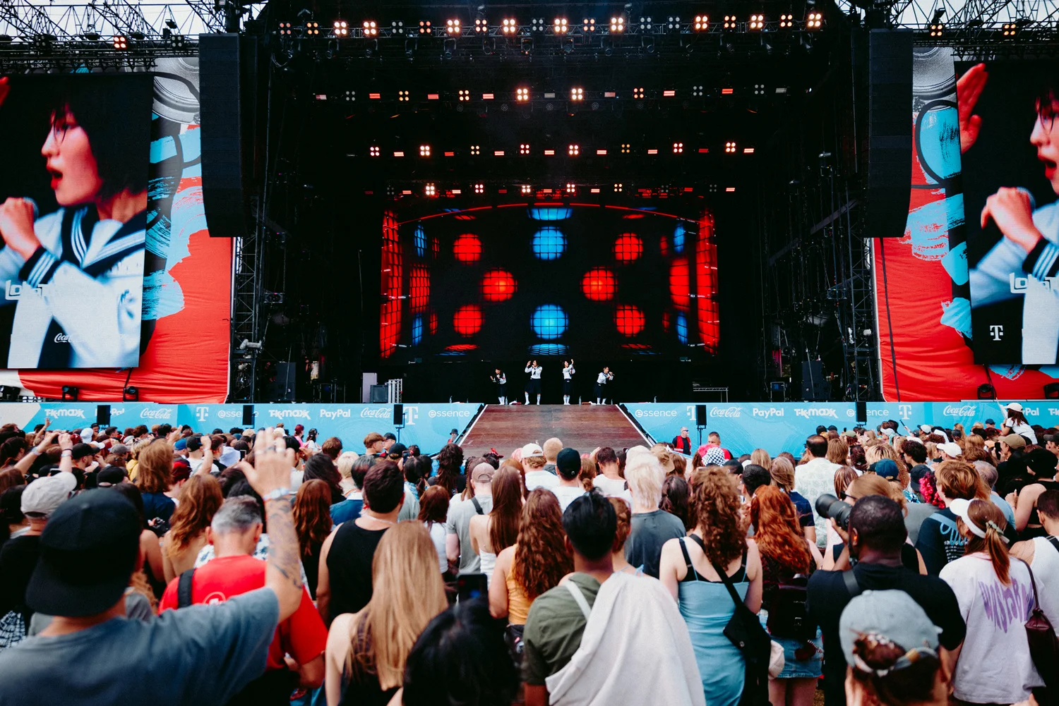 Large crowd at an outdoor concert with a colorful stage