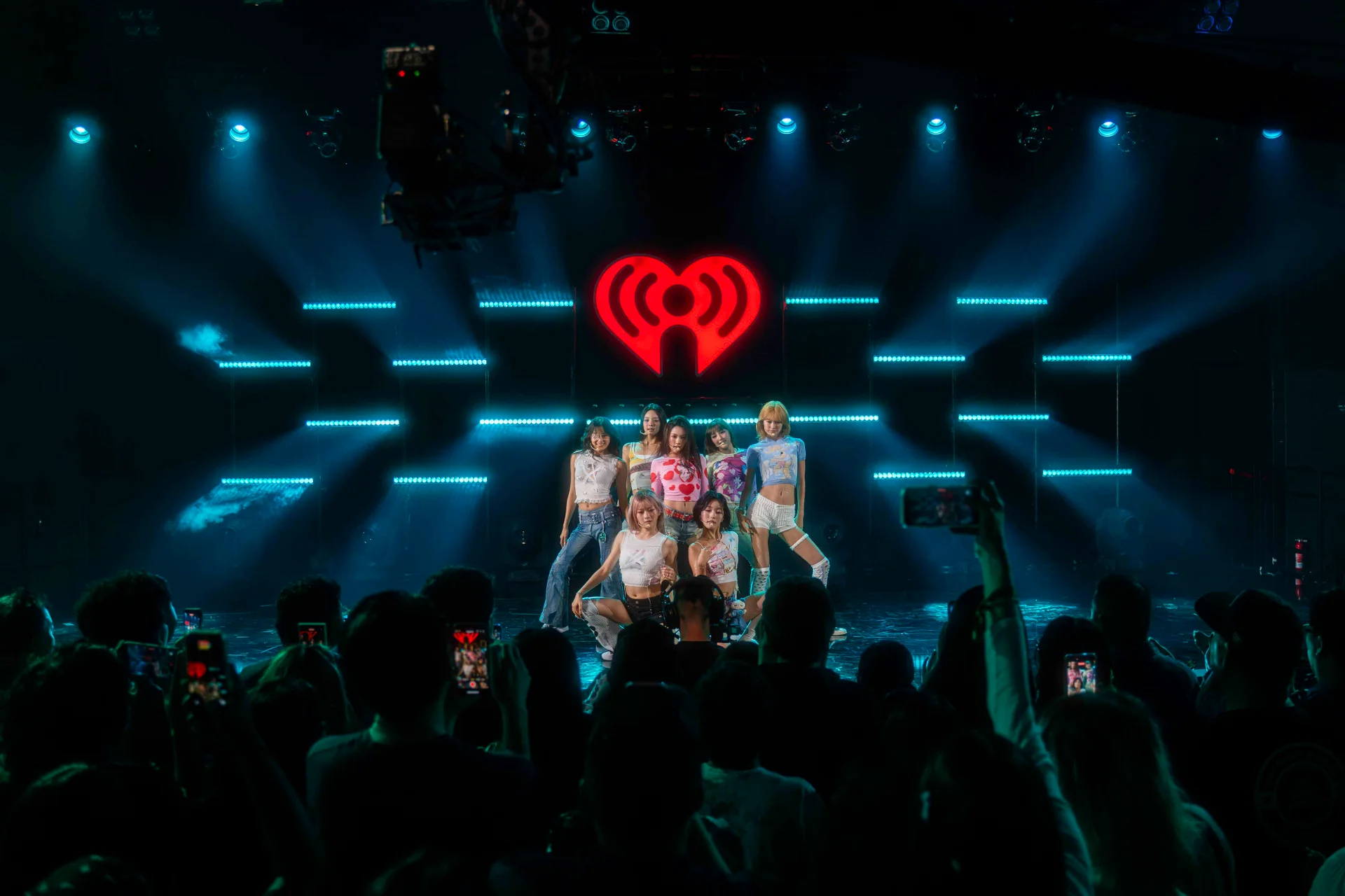 AtHeart no escenario co logo de iHeartRadio iluminado, público tirando fotos