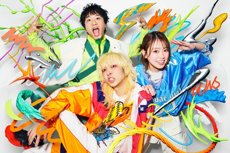 Tres membres de la banda amb vestits colorits i remolins de pintura dinàmics i vibrants al seu voltant