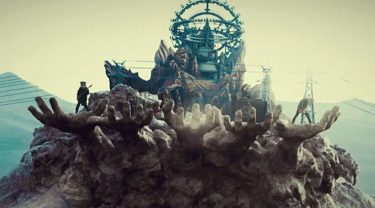 Scene from the ONE music video with large hands emerging from the ground
