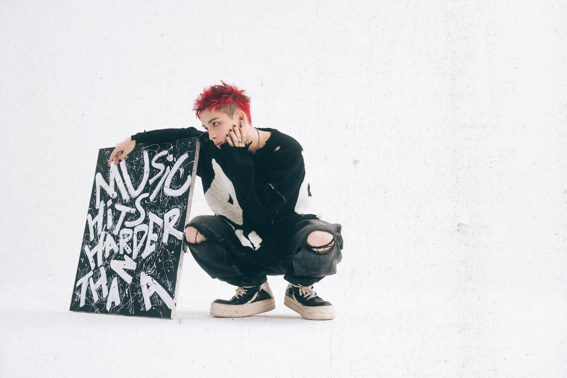 Novel Core crouching next to a sign that reads Music Hits Harder Than A