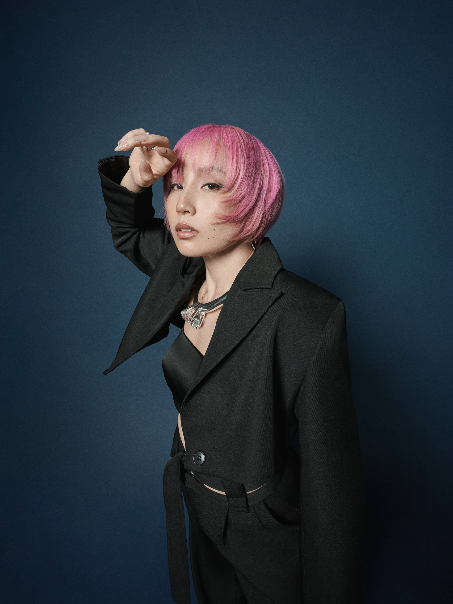 Nao Yoshioka amb una blazer negra sobre un fons fosc