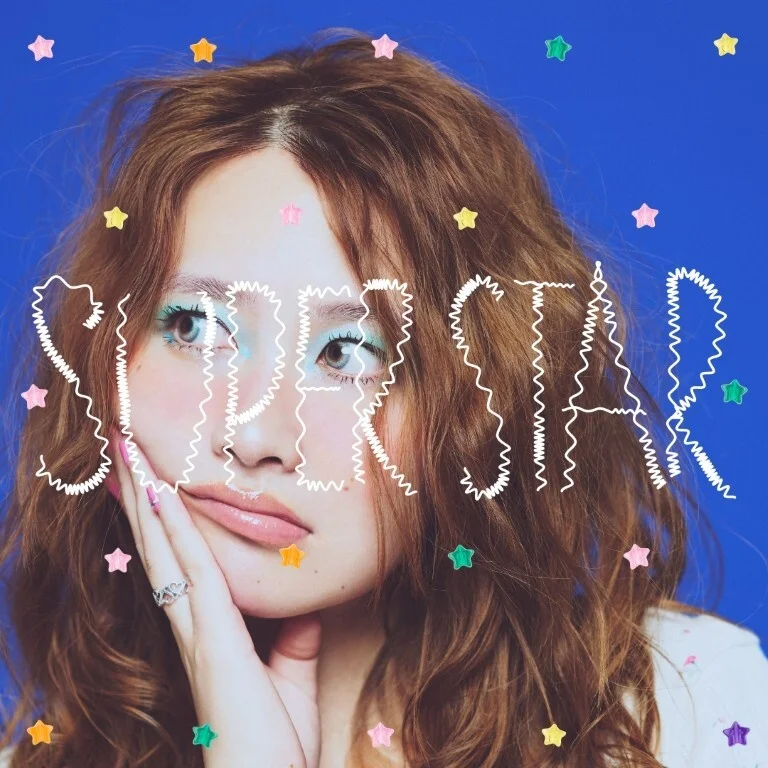 YUKA mit welligem braunem Haar vor blauem Hintergrund für die SUPERSTAR-EP