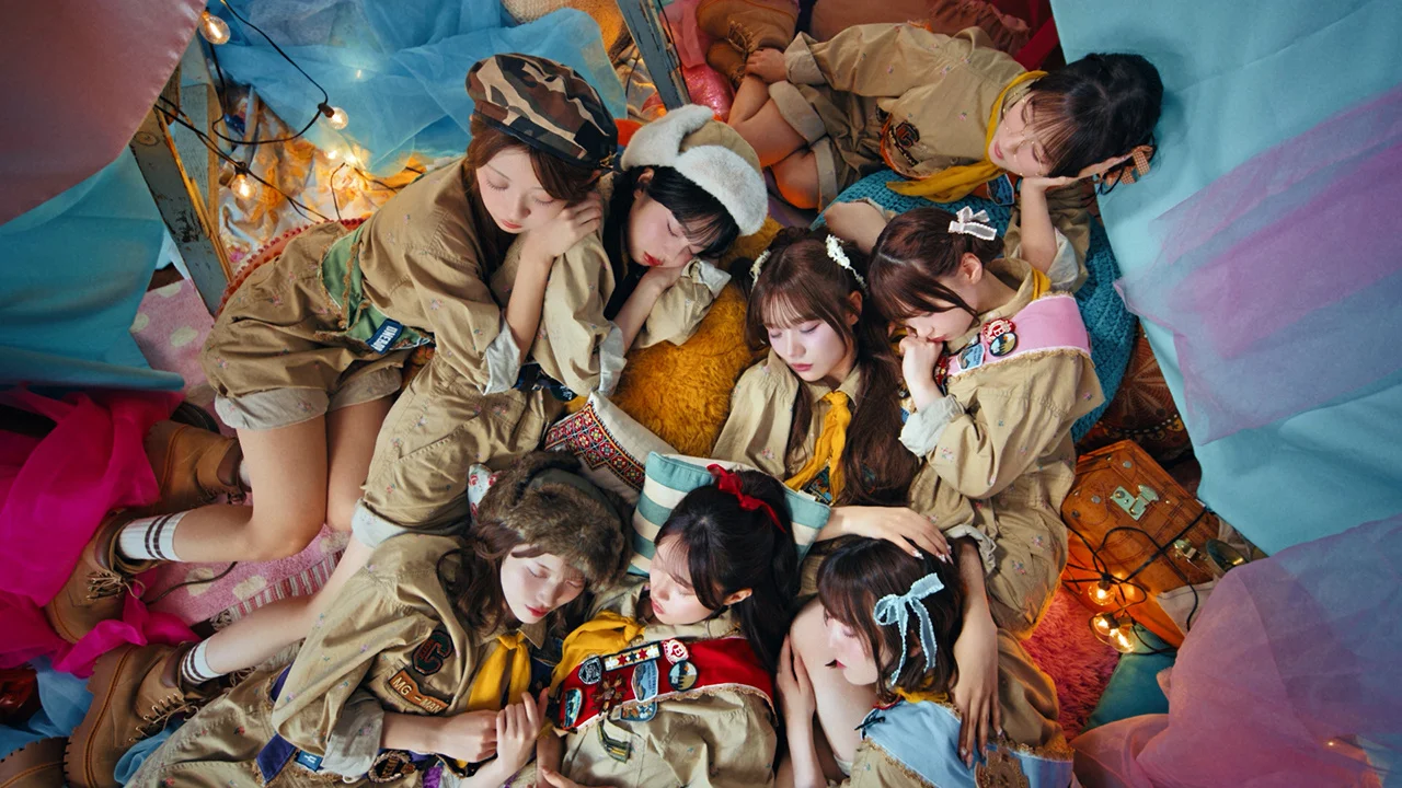 CUTIE STREET members lying on the floor surrounded by colorful fabric