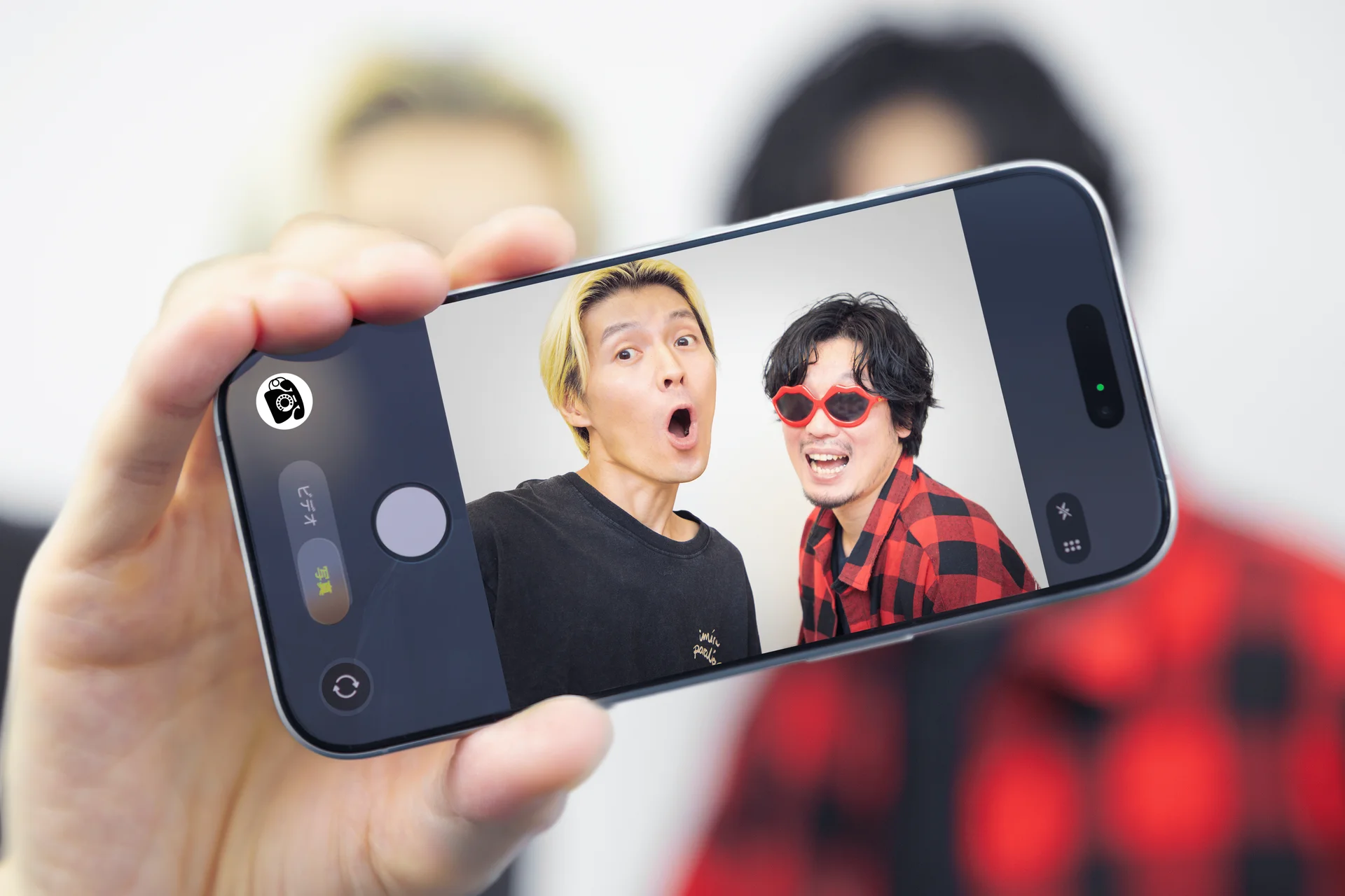 Selfie de dois membros da colaboração exibida na tela de um celular